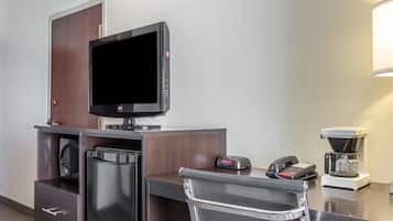 A hotel room with a desk, a flat-screen TV, a coffee maker, and a telephone.