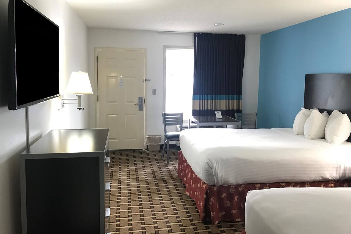 Une chambre d’hôtel équipée d’un lit, d’un bureau, d’une chaise, d’une télévision et d’une fenêtre avec des rideaux.