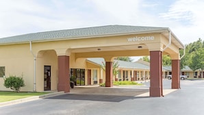 A motel with a 'welcome' sign, covered parking, and a clear sky. - Americas Best Value Inn & Suites Sumter (Sumter)