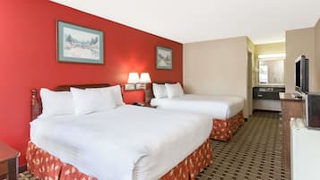 A hotel room with two beds, a TV, a desk, and a bathroom visible through an open door.