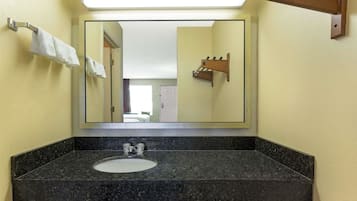 A bathroom with a granite countertop, a sink, and a mirror.