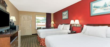 A hotel room with two beds, a TV, a desk, and a window with a view.