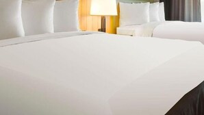 Una habitación de hotel con una cama grande, una mesita de noche, una lámpara y un cabecero de madera.