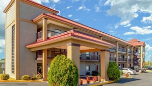 A multi-story hotel with a flat roof, balconies, and a parking lot.