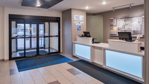 A reception area with a glass door entrance, a reception desk, and a computer station. - Holiday Inn Express & Suites Sioux Falls At Empire Mall by IHG (Sioux Falls)
