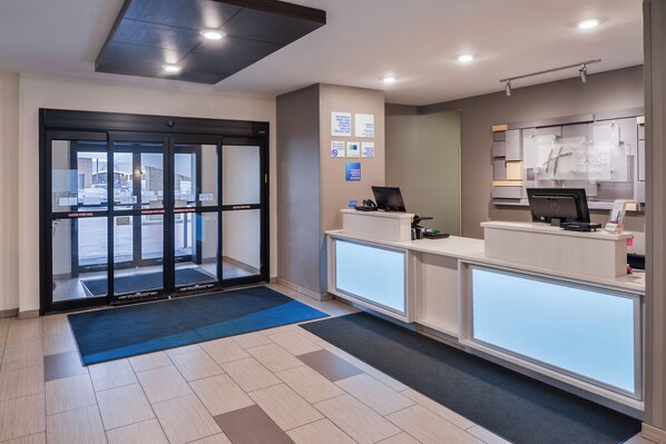 A reception area with a glass door entrance, a reception desk, and a computer station. - Holiday Inn Express & Suites Sioux Falls At Empire Mall by IHG (Sioux Falls)