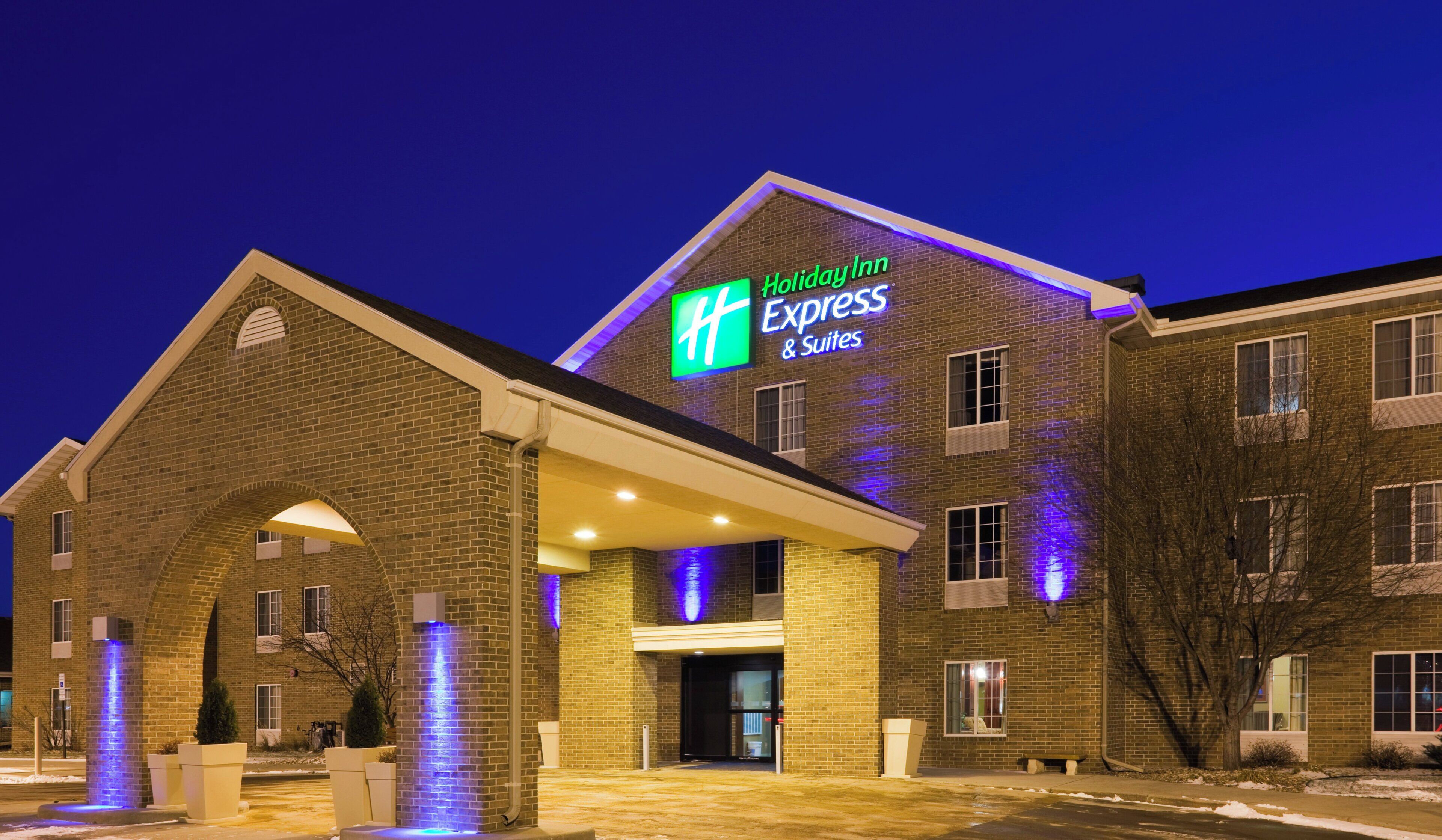 Um hotel Holiday Inn Express & Suites com fachada de tijolos e letreiros iluminados.