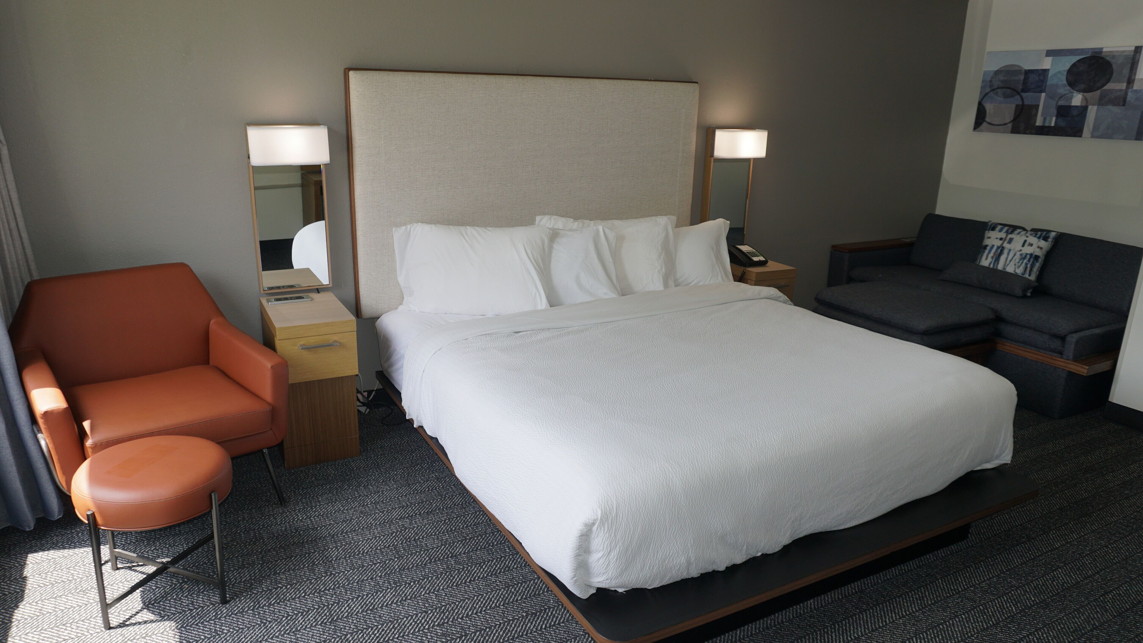 Quarto de hotel com uma cama grande, uma cadeira, uma escrivaninha e um sofá.