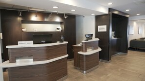 A reception area with two wooden reception desks, a seating area with a sofa, and a wall-mounted sign that reads "Marriott Bonvoy". - Courtyard by Marriott Memphis East/Bill Morris Parkway (Memphis)