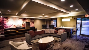 A modern hotel lobby with a sectional sofa, a white coffee table, and a bar area. - Courtyard by Marriott Memphis East/Bill Morris Parkway (Memphis)