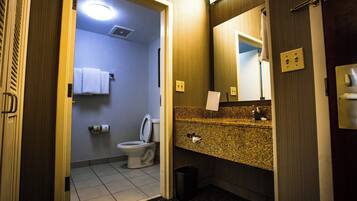 A hotel bathroom with a toilet, sink, and mirror.