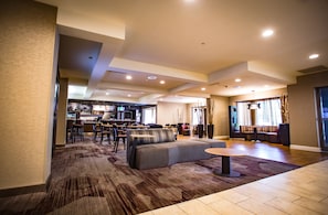 A spacious living area with a sofa, a round coffee table, and a dining area with chairs and a bar.