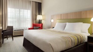 A hotel room with a large bed, a desk, a chair, and a window with curtains. - Country Inn & Suites by Radisson, Jackson, TN (Jackson)