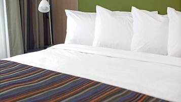 A neatly made bed with white linens and a multicolored striped bedspread.