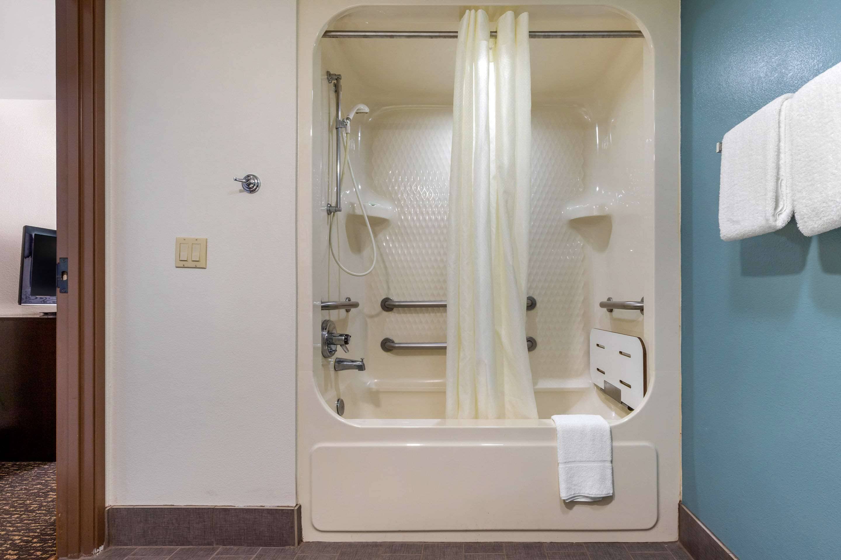 A large, walk-in bathtub with a showerhead, a towel rack, and a control panel.