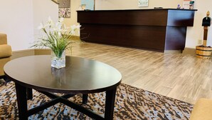 Un espace d’accueil avec un bureau en bois foncé, un vase de fleurs blanches, un tapis à motifs et un escalier en arrière-plan.
