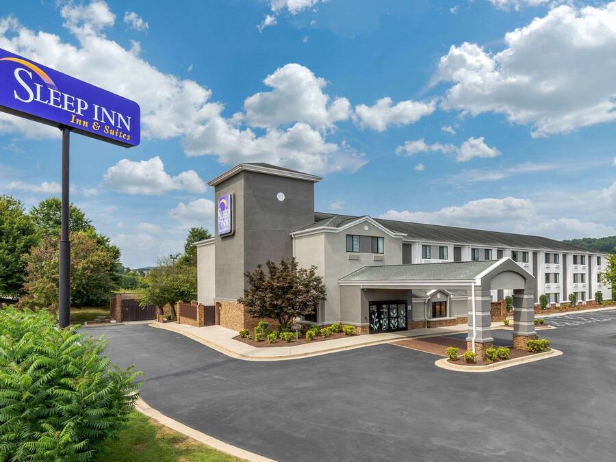 A Sleep Inn Inn & Suites building with a modern design, a parking lot, and a clear sky.