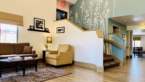 Un hall d’entrée spacieux avec un escalier, un canapé, un fauteuil et une table basse.