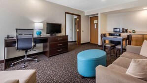 Une chambre d’hôtel équipée d’un bureau, d’une chaise, d’une télévision et d’une kitchenette.