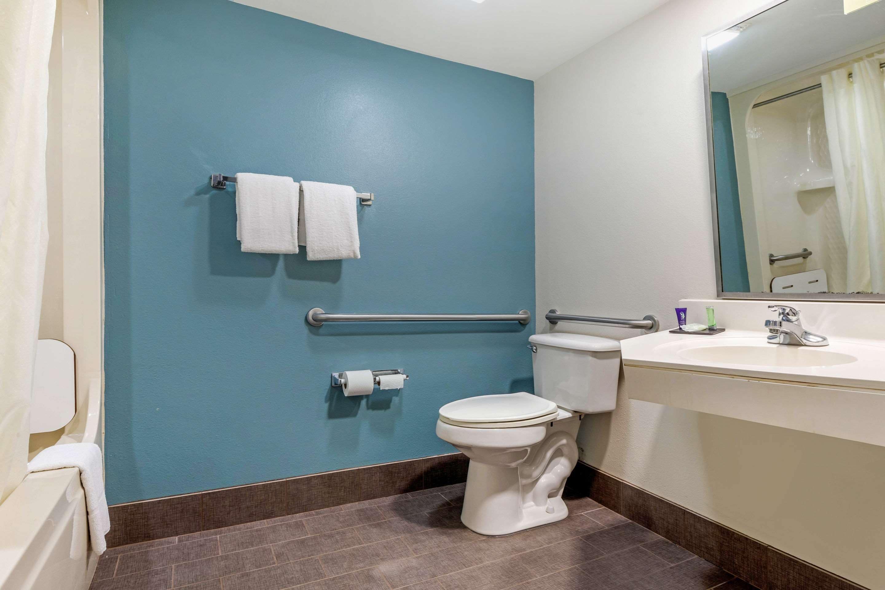 A bathroom with a blue wall, white toilet, and sink with a mirror above it.