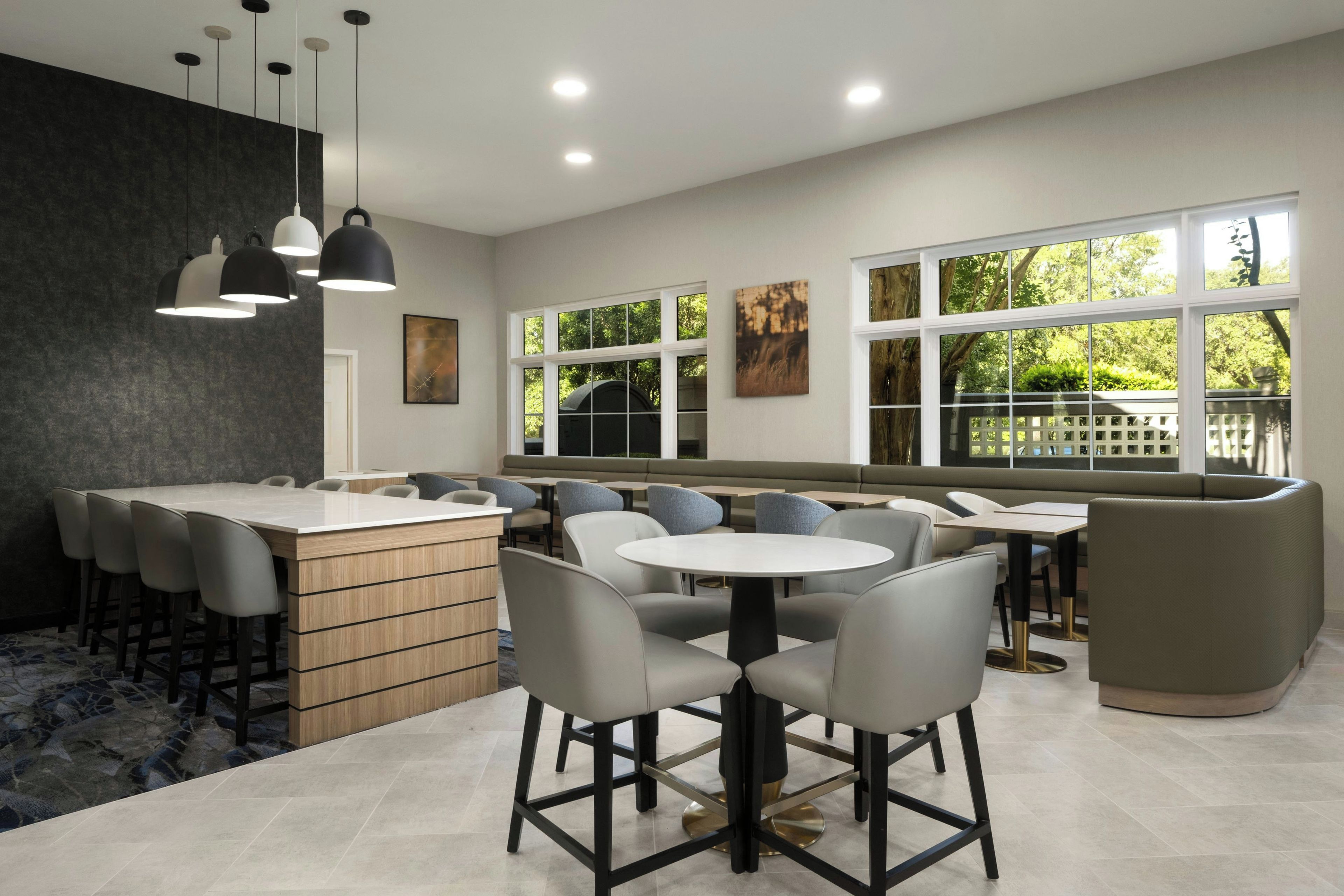 A modern dining area with a bar, seating, and large windows.