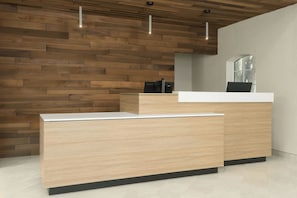 A modern reception desk with a wooden panel wall and a white countertop. - Fairfield Inn & Suites by Marriott Austin Southwest (Austin)