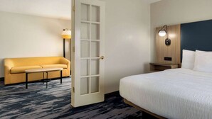 A hotel room with a bed, a sofa, a small table, a nightstand, and a lamp. - Fairfield Inn & Suites by Marriott Austin Southwest (Austin)