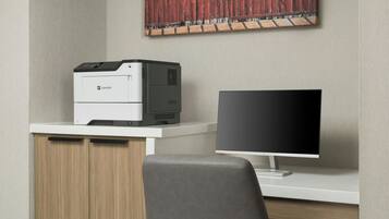 Een moderne werkplek met een printer, een computerbeeldscherm en een bureau.