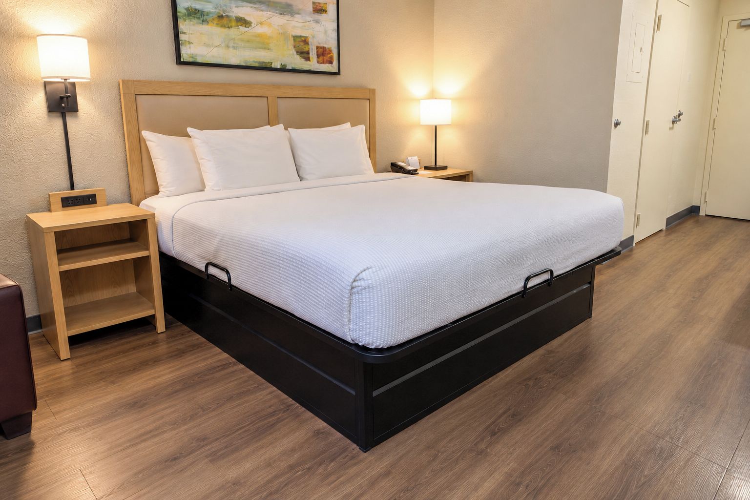 A hotel room with a bed, bedside tables, and a painting on the wall.
