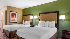Habitación de hotel con dos camas, paredes verdes y un cuadro con un arco rojo.