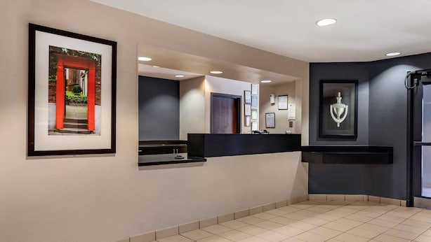 Un moderno vestíbulo de hotel con un mostrador de recepción, obras de arte enmarcadas y un suelo de baldosas.