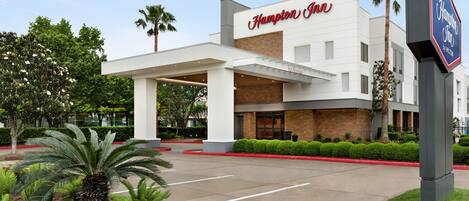 A Hampton Inn hotel with a modern facade, a welcoming entrance, and a landscaped front garden.