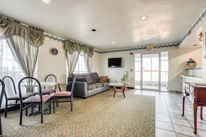 A hotel lobby with a sofa, chairs, a small table, a TV, and a patterned carpet.