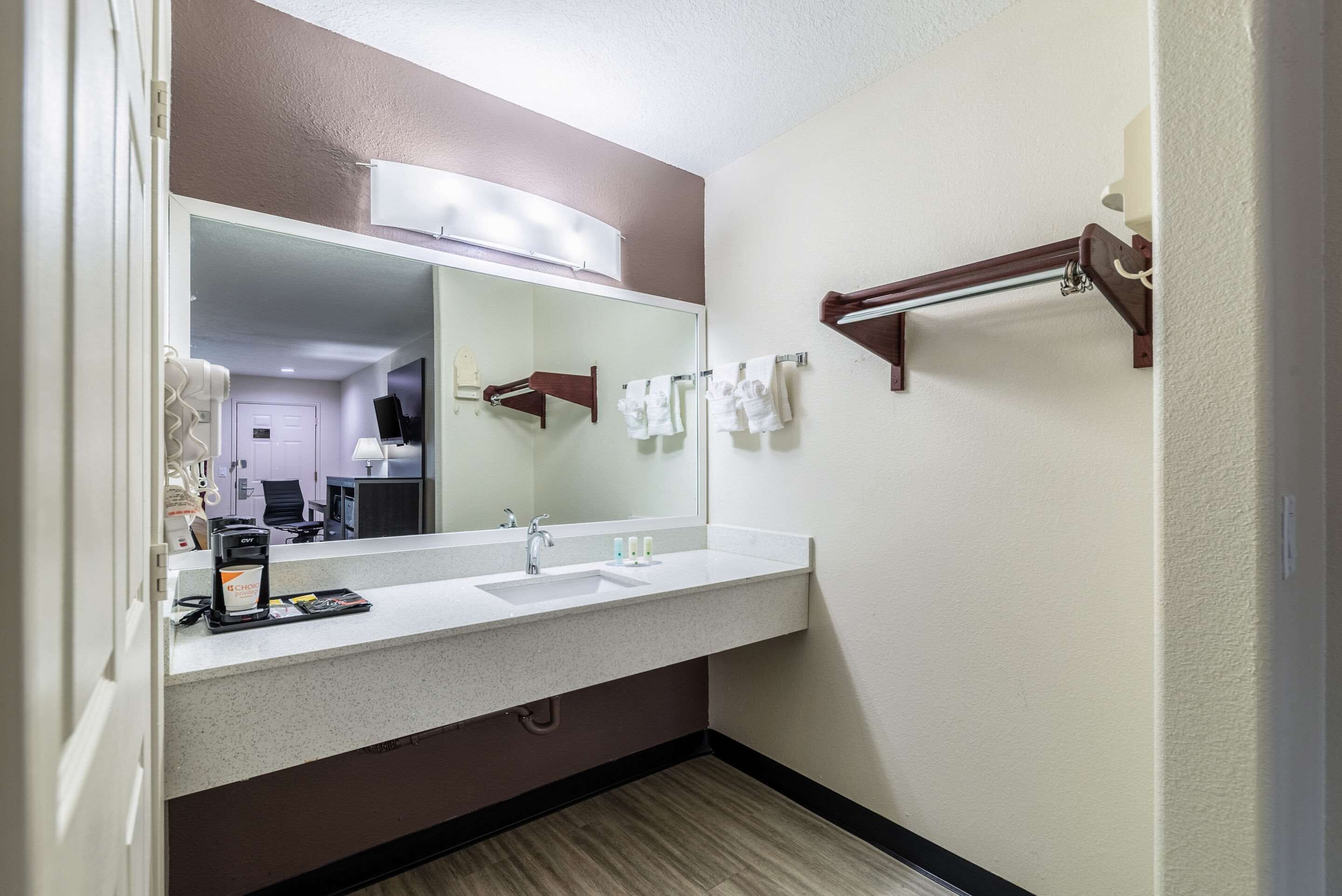 Une salle de bain avec un grand miroir, un lavabo et un porte-serviettes.