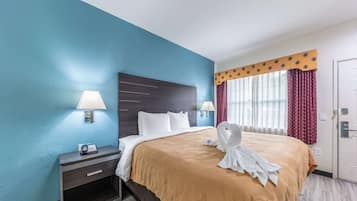 A hotel room with a bed, bedside lamps, a telephone, and a window with curtains.