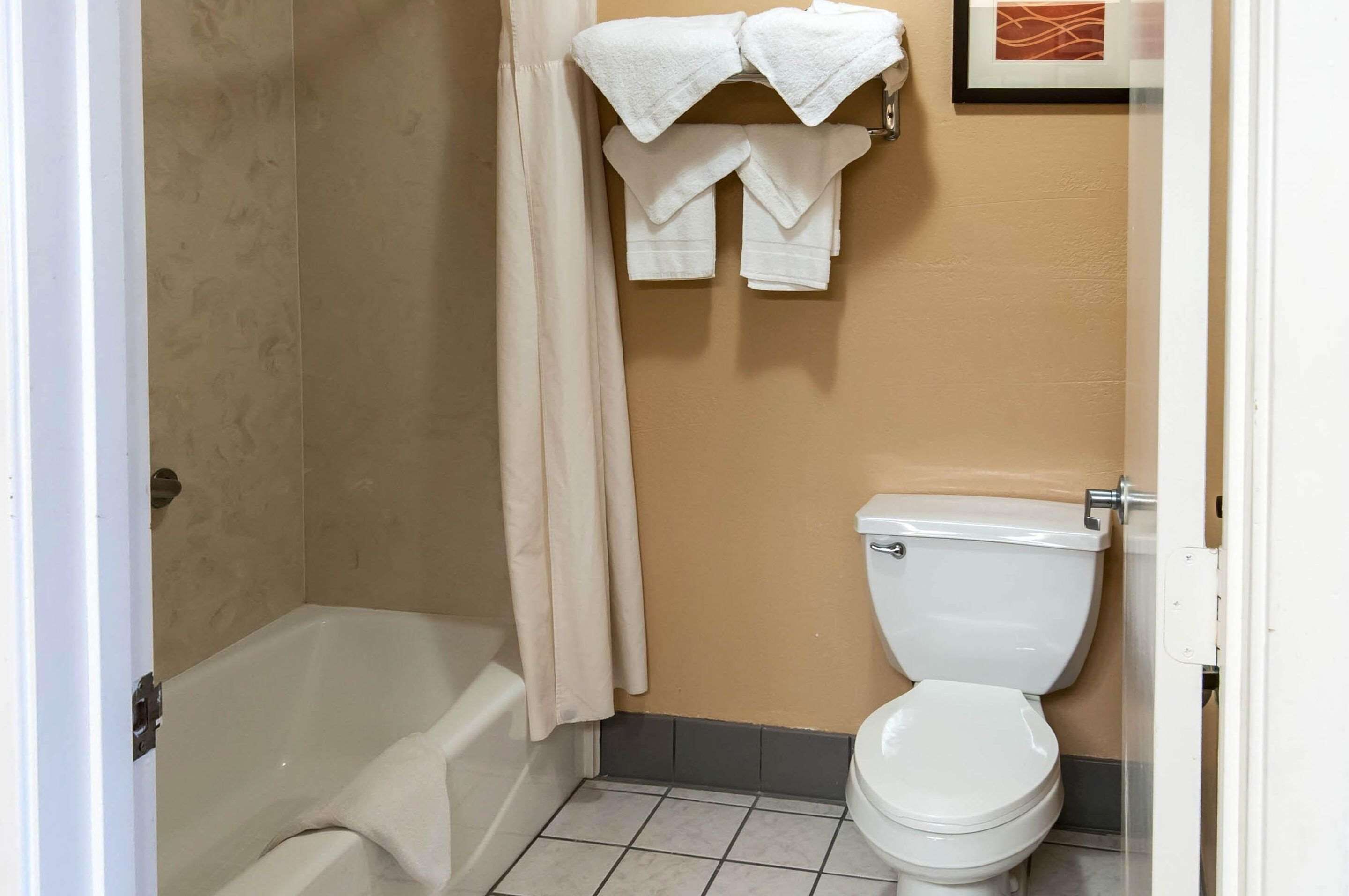 A bathroom with a bathtub, toilet, and towels hanging on a rack.