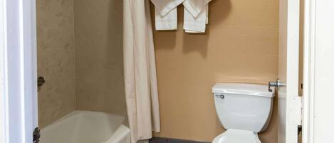 A bathroom with a bathtub, toilet, and towels hanging on a rack.