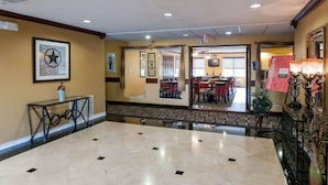 A hotel lobby with a marble floor, a reception desk, a framed artwork, and a dining area visible through an open door. - Comfort Inn North Conroe (Conroe)