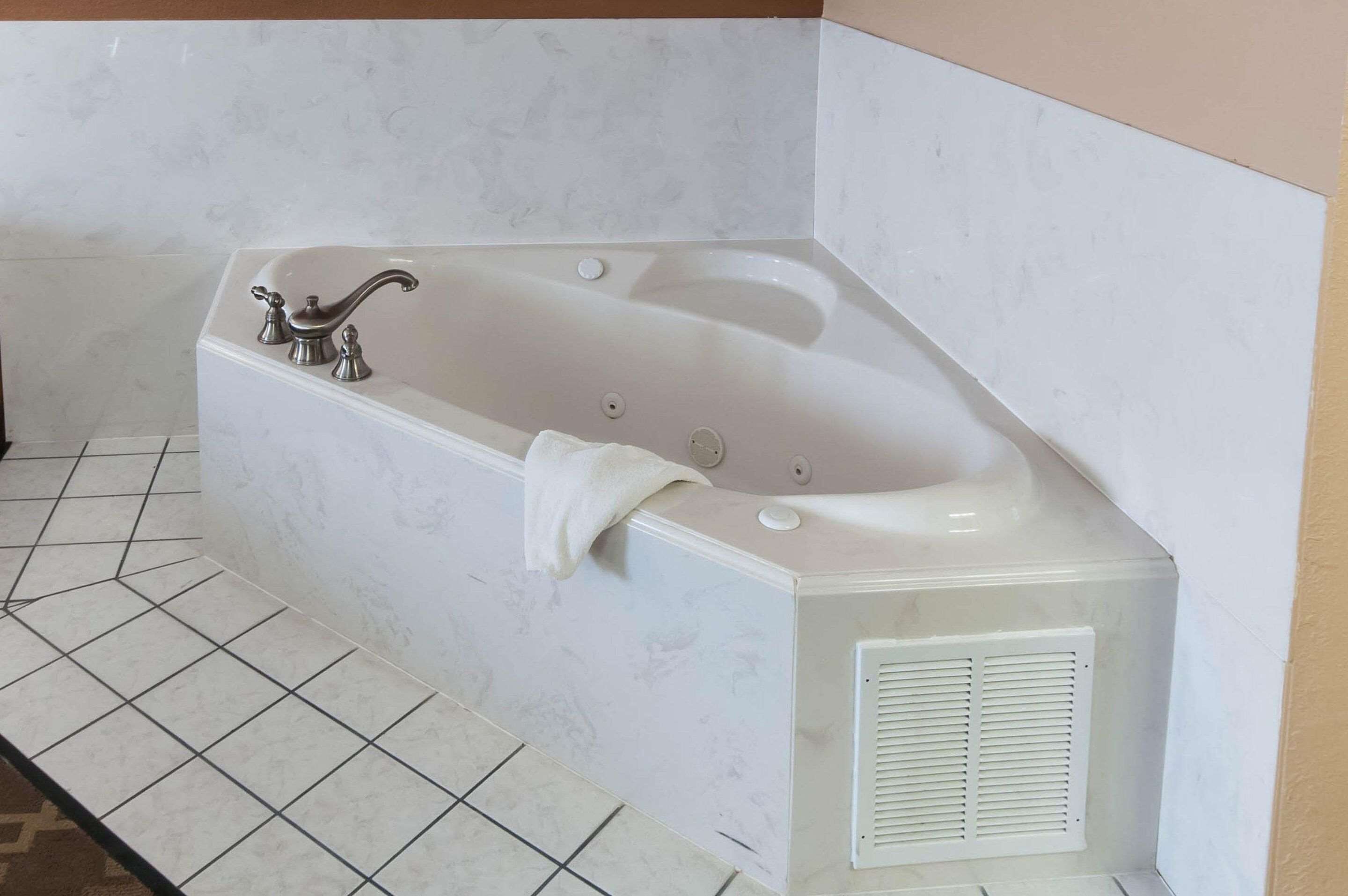 A corner bathtub with a white marble finish, a towel, and a built-in ventilation system.