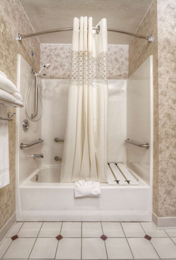 Une douche à l’italienne avec une porte en verre, une douchette à main et un porte-serviettes.
