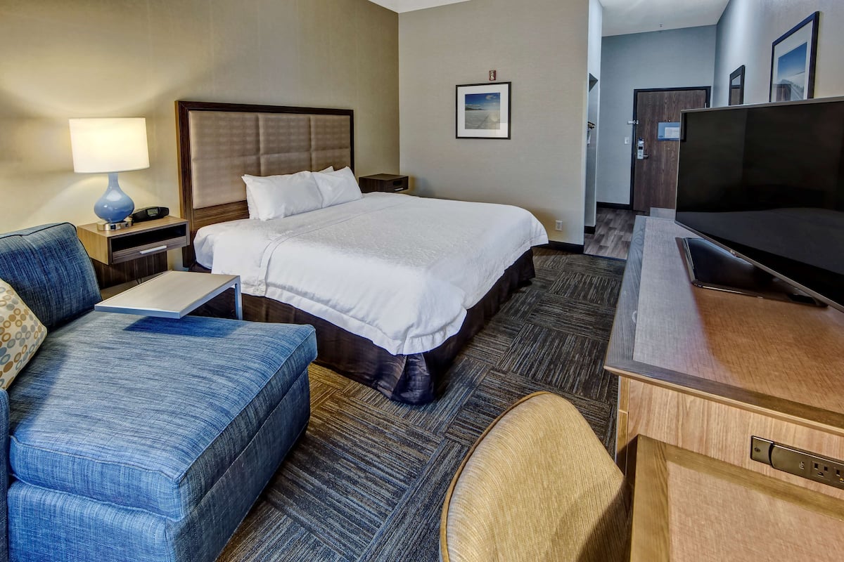 A hotel room with a bed, a TV, a desk, and a couch.