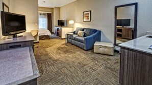 A hotel room with a flat-screen TV, a sofa, a desk, a bed, and a bathroom area. - Hampton Inn Salt Lake City/Layton (Layton)