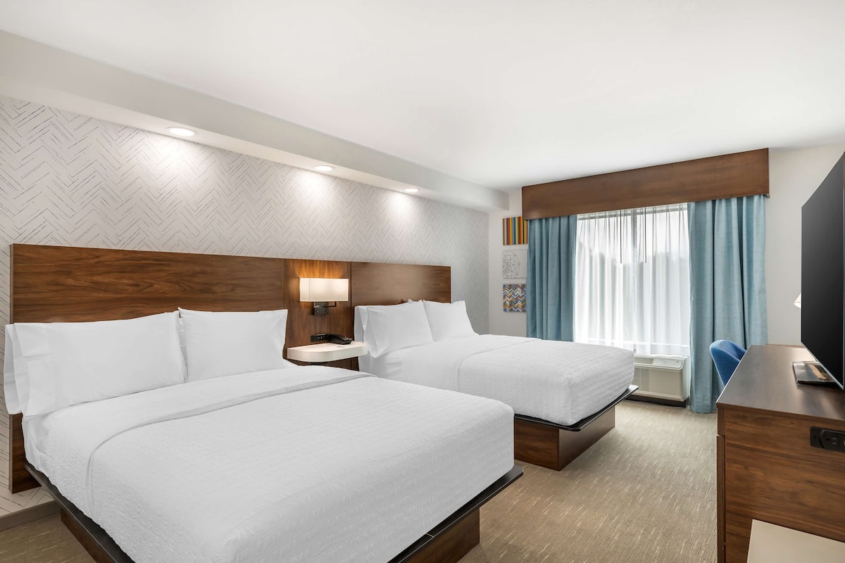 Una habitación de hotel con dos camas, un escritorio y una televisión.