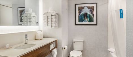A modern bathroom with a sink, mirror, toilet, and shower.