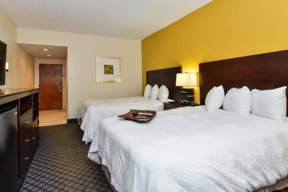 Habitación de hotel con dos camas, un escritorio, una silla, un televisor y una puerta.