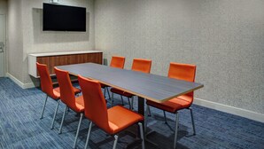 A conference room with a long table, six orange chairs, a flat-screen TV mounted on the wall, and a wooden cabinet. - Holiday Inn Express Richmond-Mechanicsville by IHG (Mechanicsville)