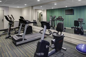A gym with various exercise equipment including treadmills, weight machines, and a stationary bike.