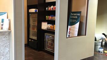Un hall d’hôtel équipé d’un kiosque en libre-service, d’un présentoir réfrigéré et d’une enseigne promotionnelle pour un programme de fidélité.