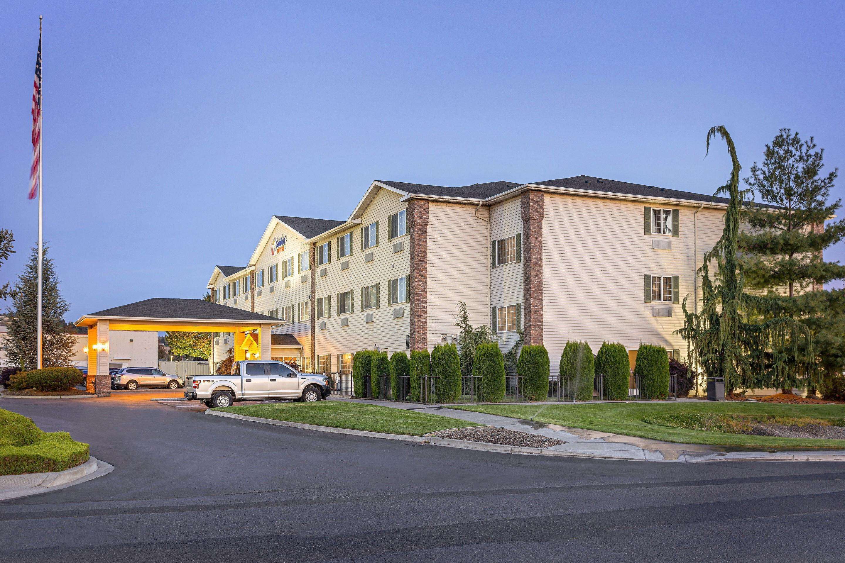 A multi-story hotel with a parking lot and a flagpole.