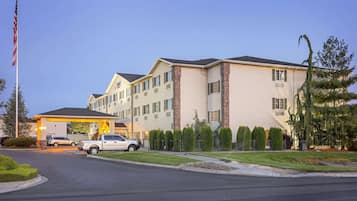 A multi-story hotel with a parking lot and a flagpole.